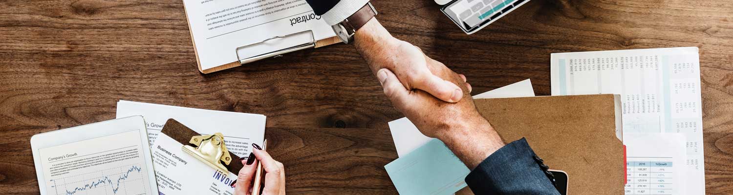 two business men shaking hands over documents